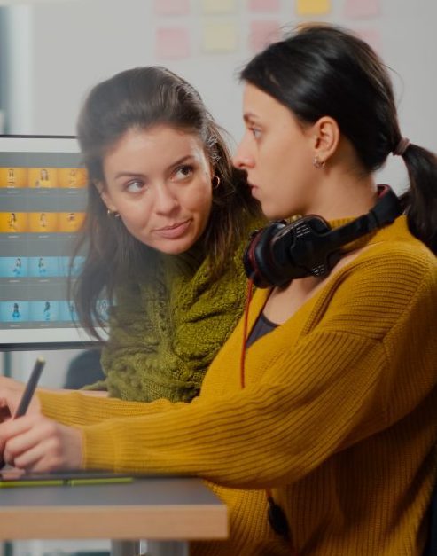 Confident women photo editors sitting at workplace in creative studio