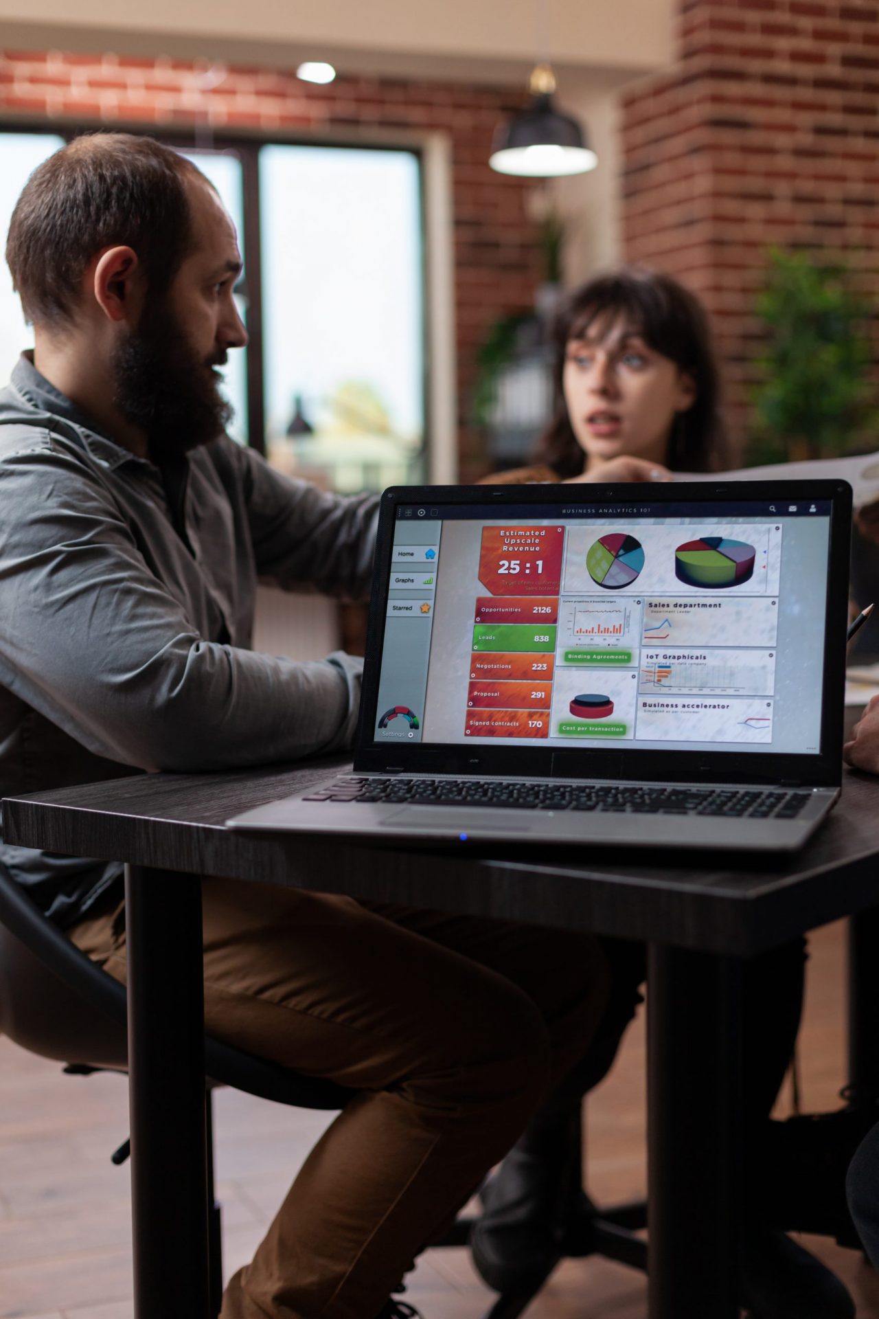 laptop-computer-having-marketing-project-graphs-screen-while-multiethnic-businesspeople-discussing-company-turnover-startup-office-diverse-team-planning-business-collaboration