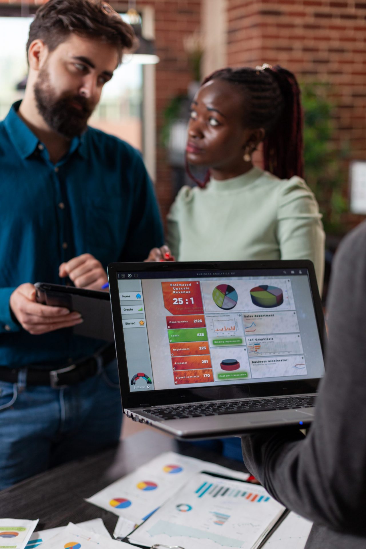 multiracial-businesspeople-analysing-company-turnover-discussing-business-collaboration-while-working-brick-wall-startup-office-mult-ethnic-team-brainstorming-ideas-marketing-project