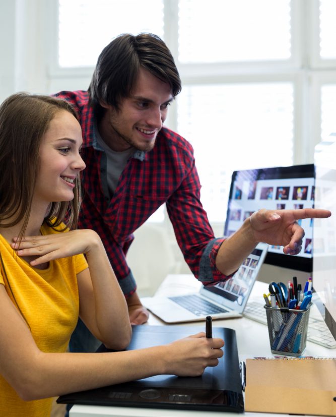 Male and female website developer interacting over computer